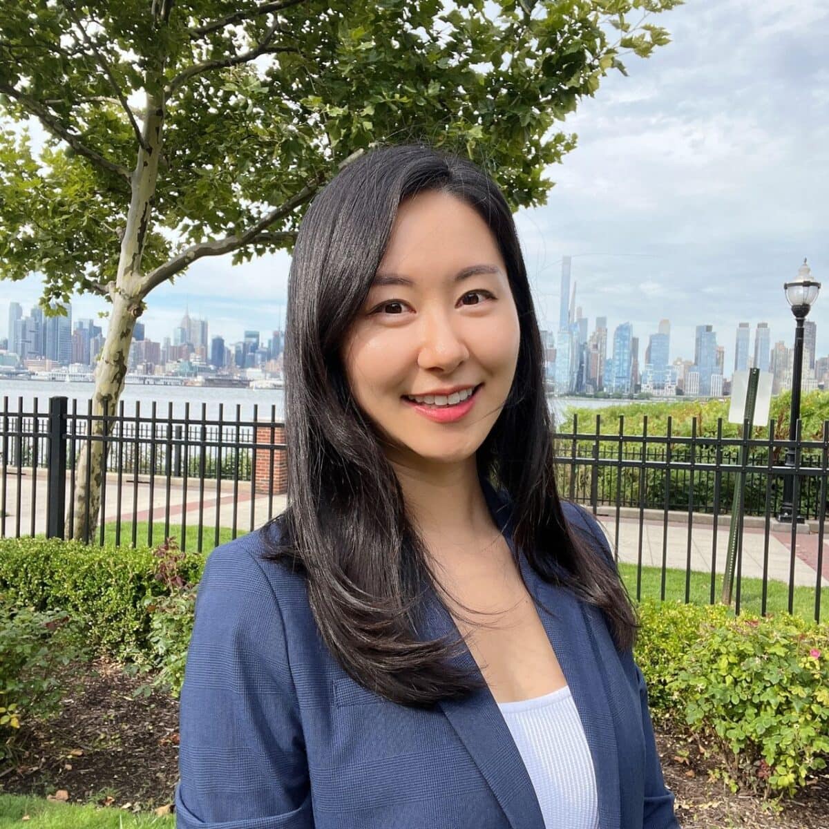 Friendly ALT tag: Professional woman smiling outdoors with city skyline in the background at SIIM Annual Meeting.