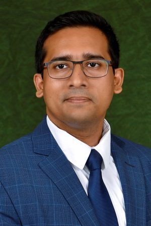 A man in a blue suit and glasses attending the SIIM Annual Meeting, engaging in professional medical imaging discussions.