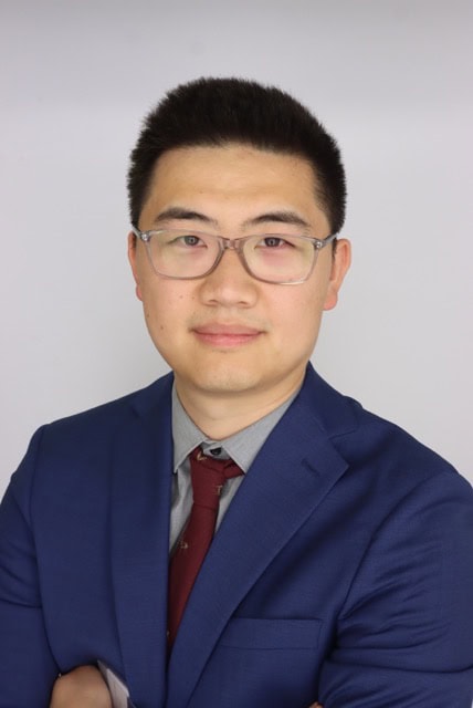 Professional portrait of Tubo Shi, MBChB, FRANZCR, attending the SIIM Annual Meeting, showcasing a medical imaging expert in formal attire.