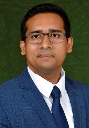 A man in a blue suit and glasses attending the SIIM Annual Meeting, engaging in professional medical imaging discussions.
