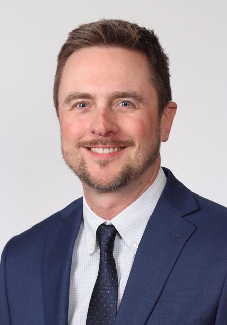 Professional headshot of Jason Klug, PhD, attending the SIIM Annual Meeting, showcasing a confident smile and business attire.