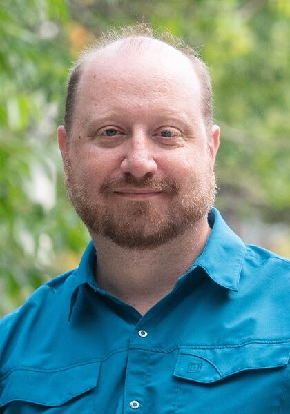 A man with a beard and blue shirt attending the SIIM Annual Meeting outdoors, engaging with healthcare professionals and showcasing medical imaging technology.