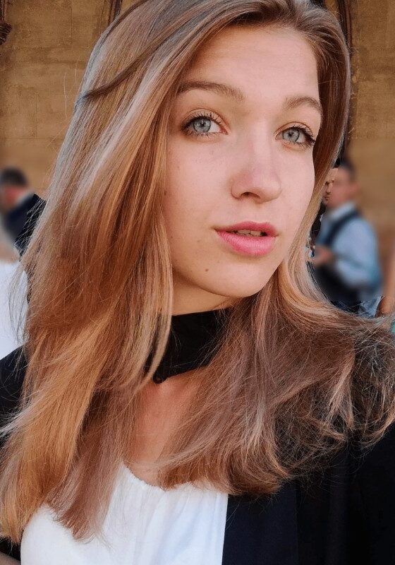 High-resolution portrait of a young woman with blue eyes and strawberry blonde hair at the SIIM Annual Meeting, showcasing attendees engaging in medical imaging and radiology innovations, vibrant event atmosphere.