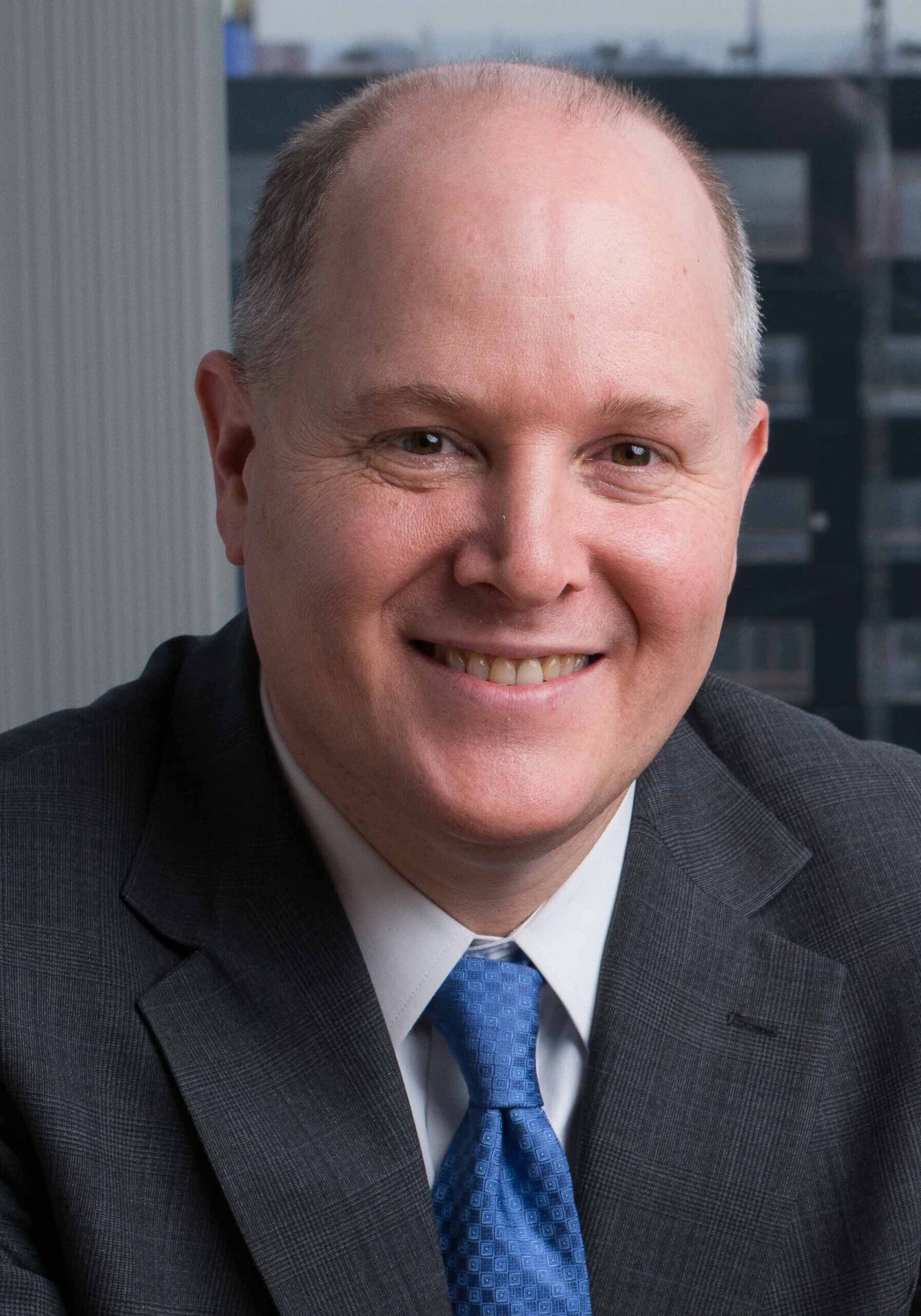 A professional headshot of a smiling man in a business suit at the SIIM Annual Meeting, emphasizing healthcare imaging and medical informatics.