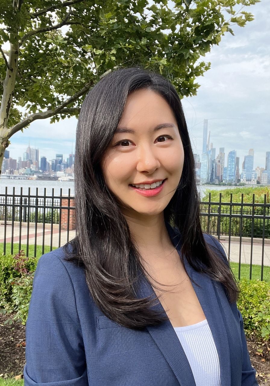 Friendly ALT tag: Professional woman smiling outdoors with city skyline in the background at SIIM Annual Meeting.