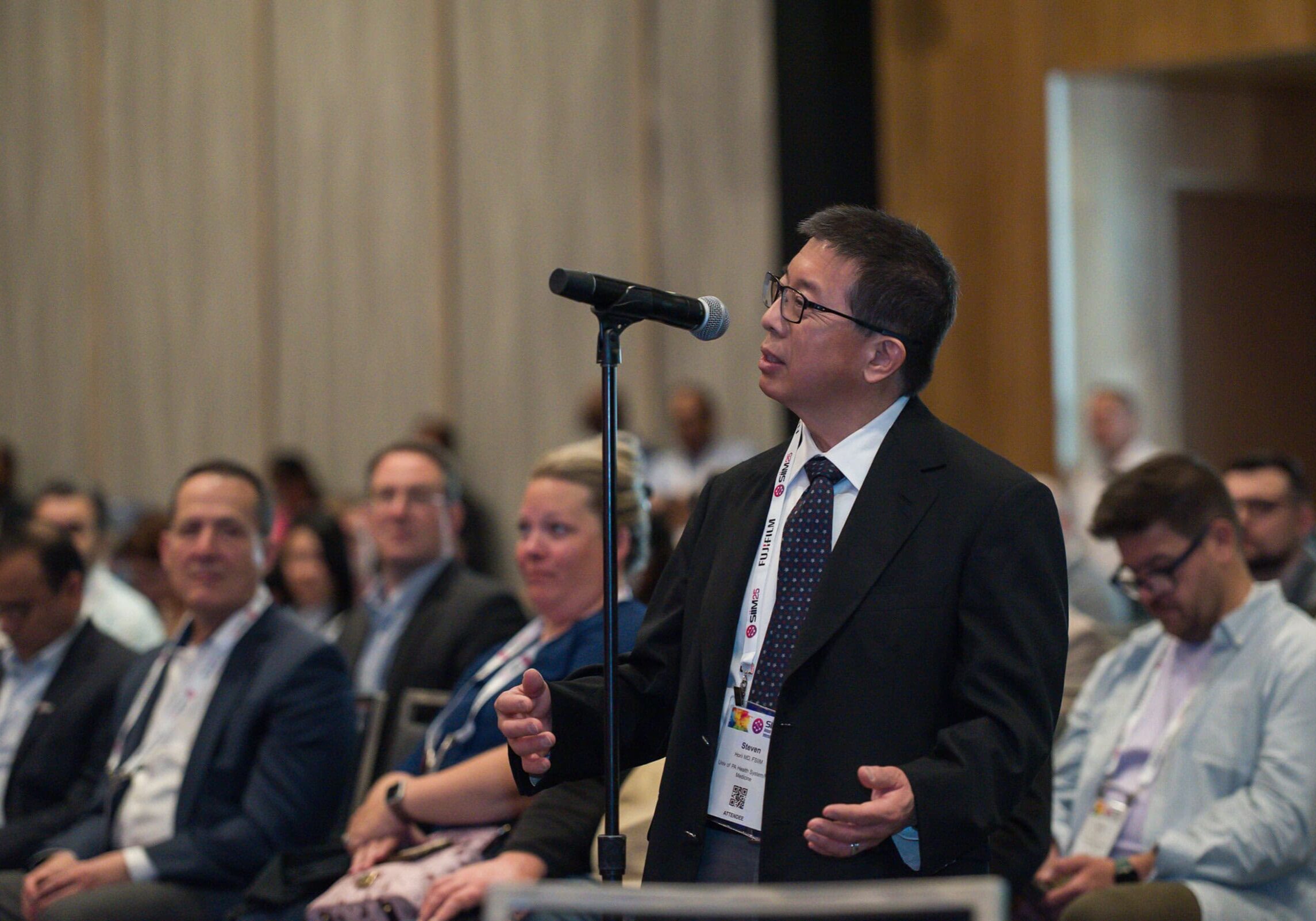 An engaged conference attendee asks a question during the SIIM Annual Meeting, highlighting medical imaging innovation and professional networking at this prominent healthcare informatics event.