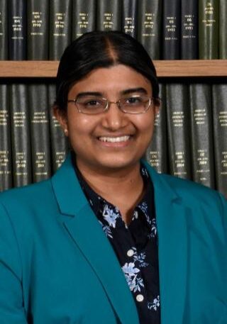 AI-generated medical professional smiling in front of a bookshelf at the SIIM Annual Meeting, showcasing radiology and medical imaging expertise.