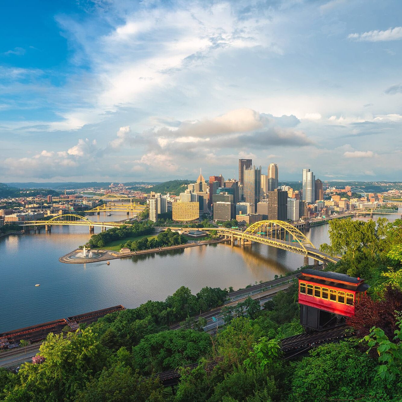 1. A scenic view of downtown Pittsburgh with the skyline, rivers, bridges, and lush greenery during daytime, promoting the SIIM Annual Meeting in a vibrant city setting.