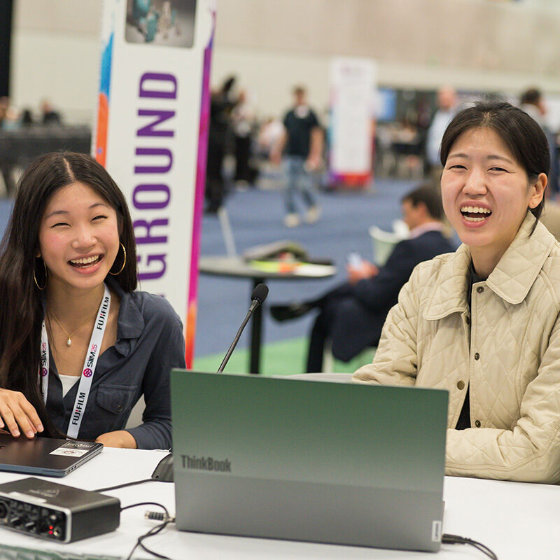 Happy women at the SIIM Annual Meeting discussing innovative medical imaging technology and radiology solutions in a dynamic conference environment.