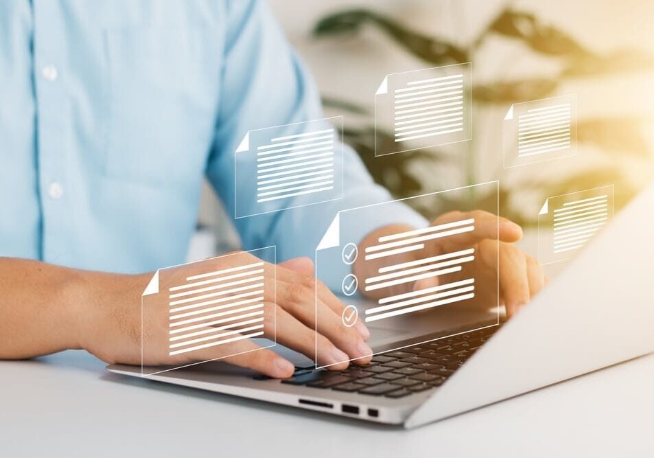 Person working on a laptop with digital document icons floating above, representing data management at the SIIM Annual Meeting.